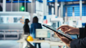 Profissional de facilities utilizando tablet em ambiente corporativo, destacando os serviços e benefícios de uma gestão eficiente de instalações.